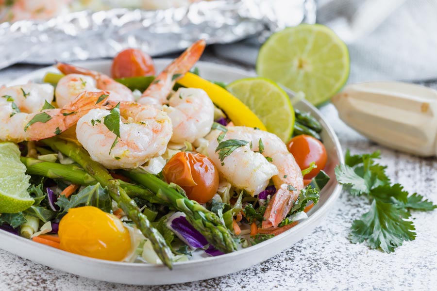 a bright shrimp salad with roasted veggies and lime wedges
