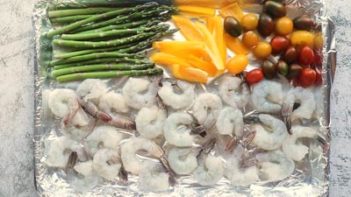 raw shrimp and veggies on a baking sheet