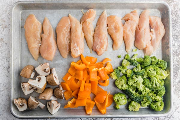 chicken tenders, mushrooms, bell pepper and broccoli on a sheet pan