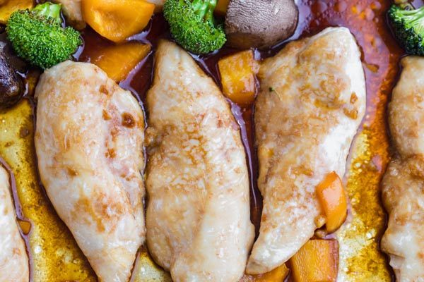 three teriyaki chicken tenders on a tray with bell pepper and broccoli