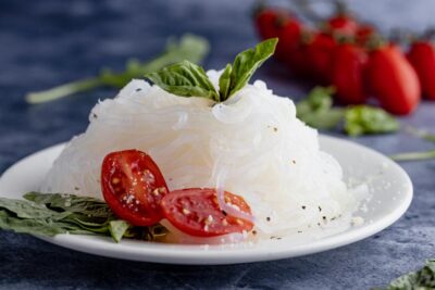 shirataki pasta on a plate with tomatoes and basil