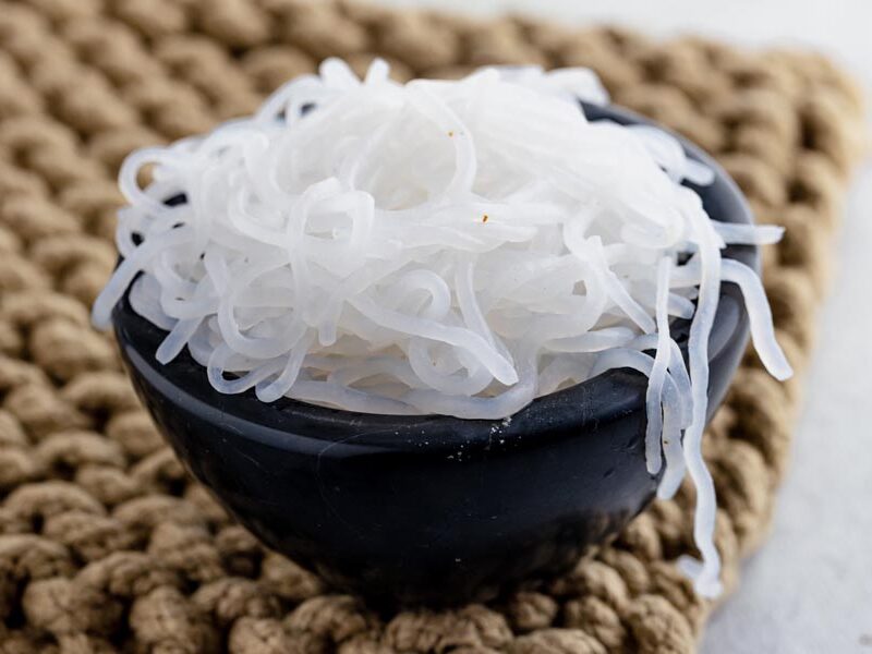 a black bowl filled with konjac noodles on a burlap pad