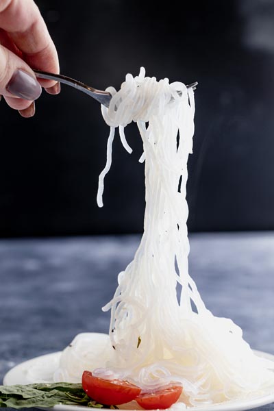 holding a string of pasta with a fork