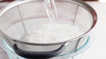 pouring water into a colander filled with noodles