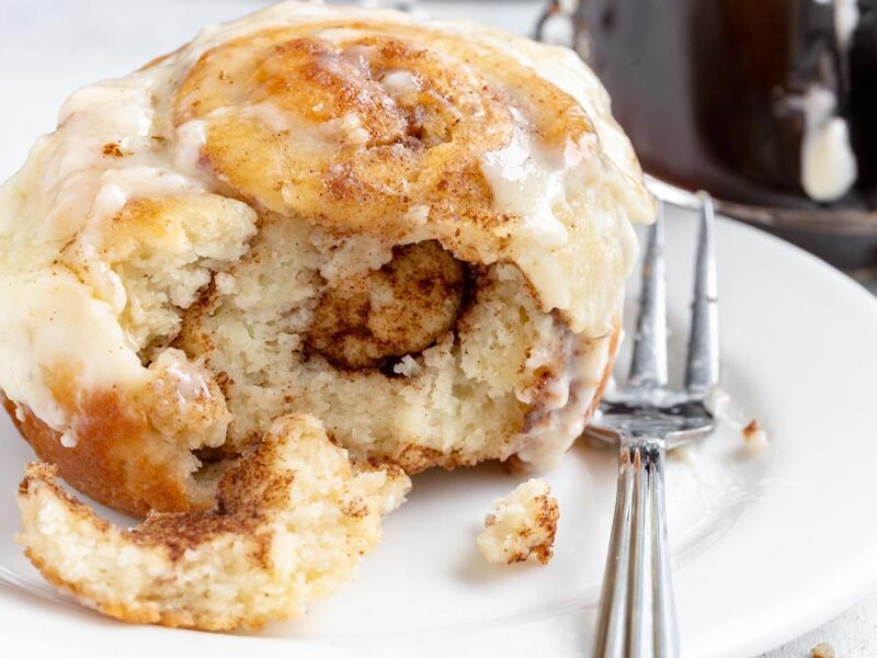 Keto cinnamon roll with a bite missing, showing its buttery cinnamon swirl.
