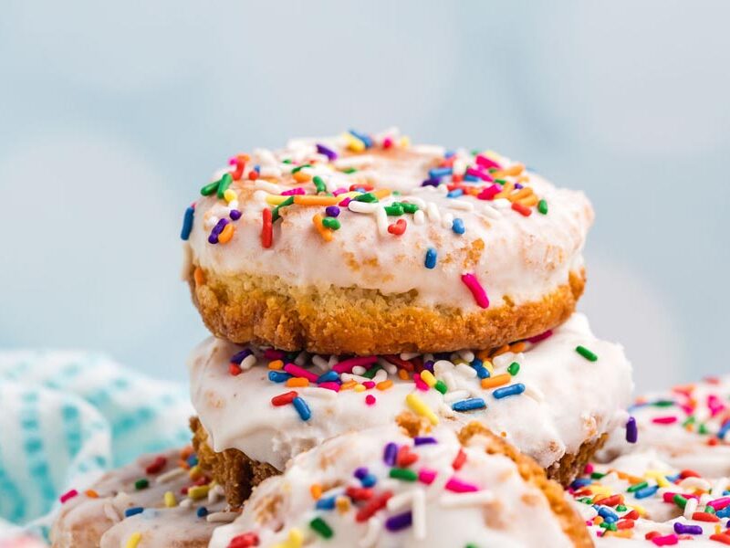 A stack of keto donuts covered in vanilla glaze and sprinkles.