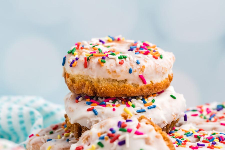 A stack of keto donuts covered in vanilla glaze and sprinkles.
