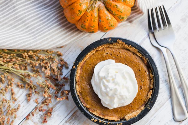 overhead view of mini pumpkin pie with a pumpkin and forks near