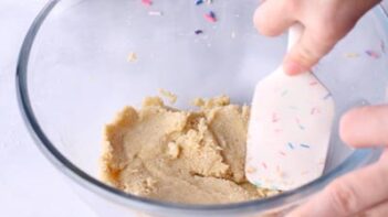 A sprinkled spatula mixing cookie dough in a bowl.