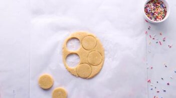 Circle cut out of flatten, rolled cookie dough on a sheet of parchment paper.