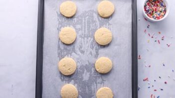 Baked sugar cookies on a parchment lined baking sheet.