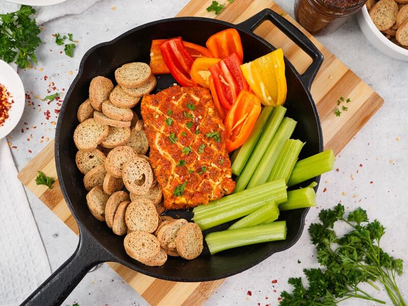 Smoked cream cheese in a skillet with celery, mini peppers and toasted bread rounds.