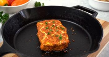 A skillet with smoked cream cheese topped with honey and minced parsley.