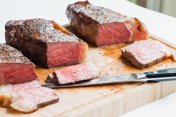 three sous vide NY steaks on a cutting board