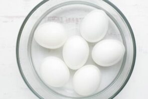 Six white eggs in a bowl of ice water.