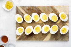 Hard boiled eggs sliced in half with mustard neaby.