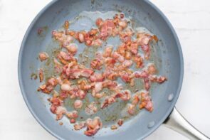 Bacon bits cooking in a skillet.