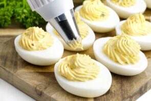 Piping yolk filling into the egg white part of a deviled egg.