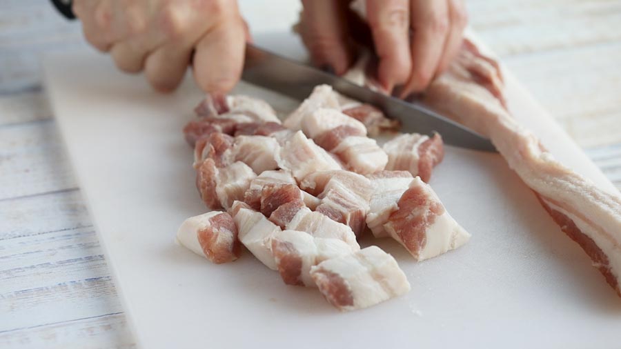 cutting up pork belly with a knife