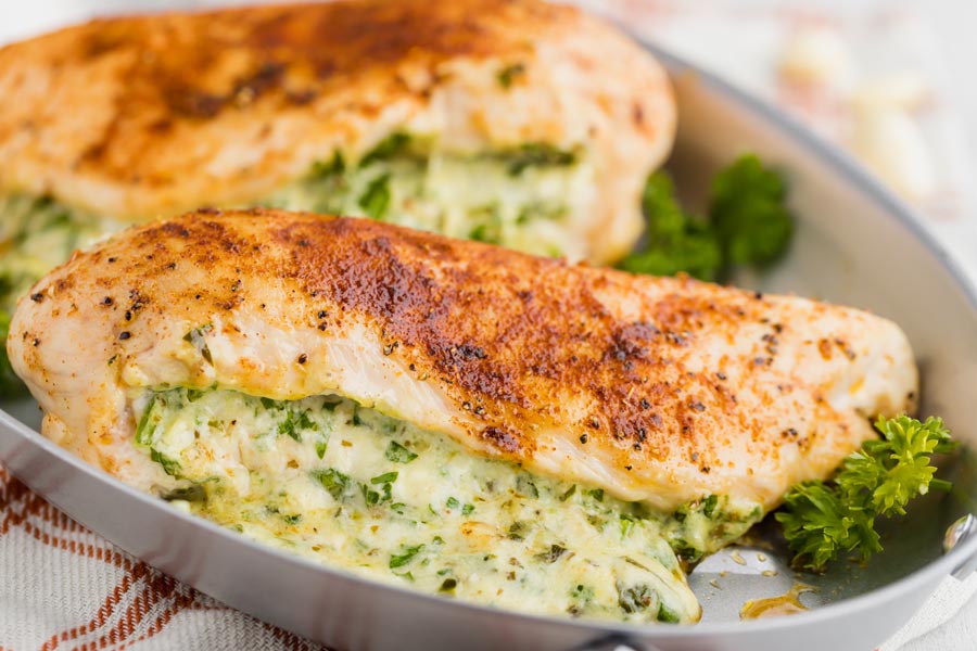 seasoned chicken in a skillet with chopped spinach cheese mixture stuffed inside