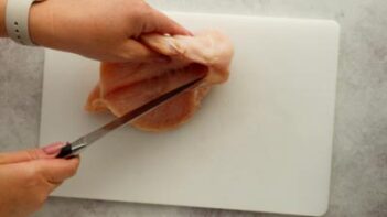 using a knife to cut a pocket slit into the center of a chicken breast
