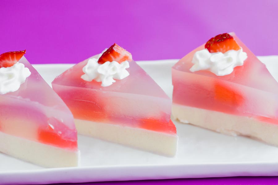 Close-up of three vibrant stained glass cake slices showing clear layers of gelatin and cream.