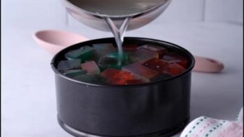 Clear liquid agar mixture being poured over the colored cubes to form the top layer of the cake.