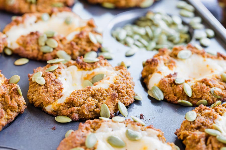 baked pumpkin muffins in a tray topped with pumpkin seeds