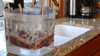 bagged steaks clipped to sous vide pot