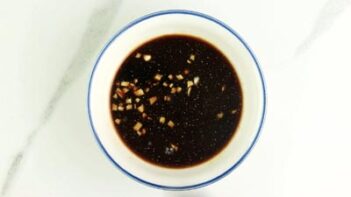 a small white bowl with soy sauce and garlic inside