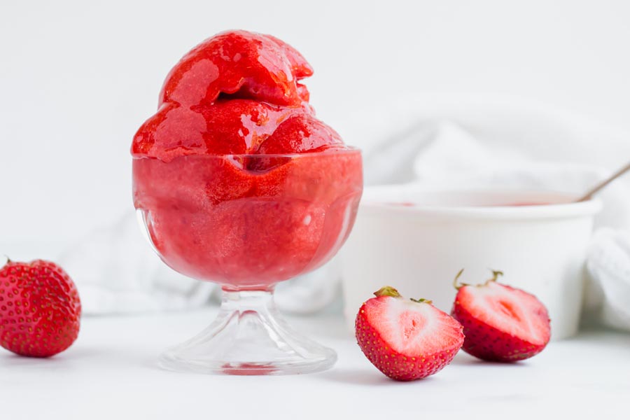 a dish with frozen sorbet inside with strawberries surrounding
