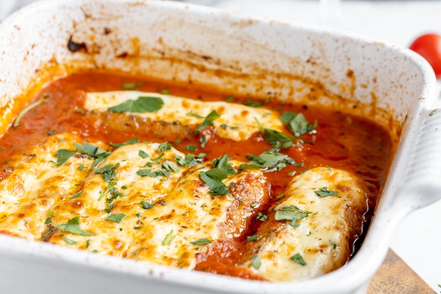 a white baking dish with cheese covered sausages in marinara sauce