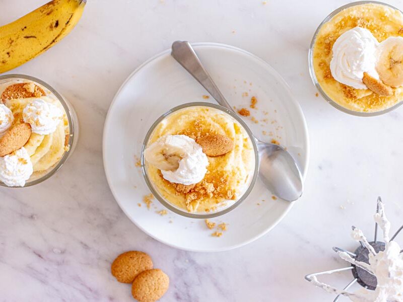 Looking down into three small bowls with banana pudding and topped with whipped cream and vanilla wafers.