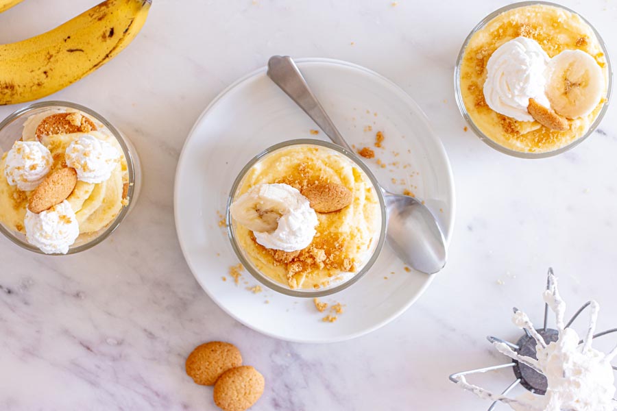 Looking down into three small bowls with banana pudding and topped with whipped cream and vanilla wafers.