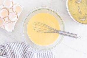 Thickened pudding in a glass bowl next to egg shells and a towel.