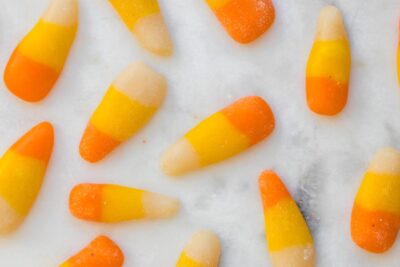 A close-up of homemade sugar-free candy corn arranged on a marble surface, showcasing the distinct white, yellow, and orange layers.