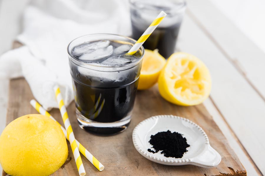 a glass of detox sugar free lemonade with a striped yellow straw and ice