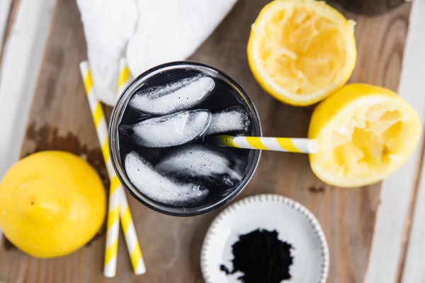 black flecks of charcoal in a black detox lemonade drink