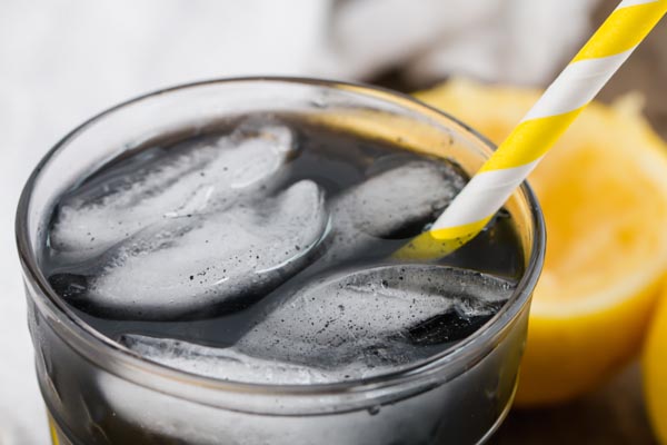 a large cold glass of black detox lemonade with ice cubes