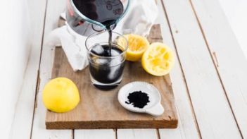 pouring sugar free charcoal lemonade into a glass with ice