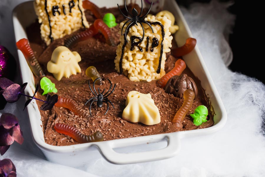 spooky dark chocolate garveyard cake covered in spiders and worms
