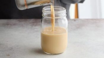 Pouring sugar free condensed milk into a mason jar.