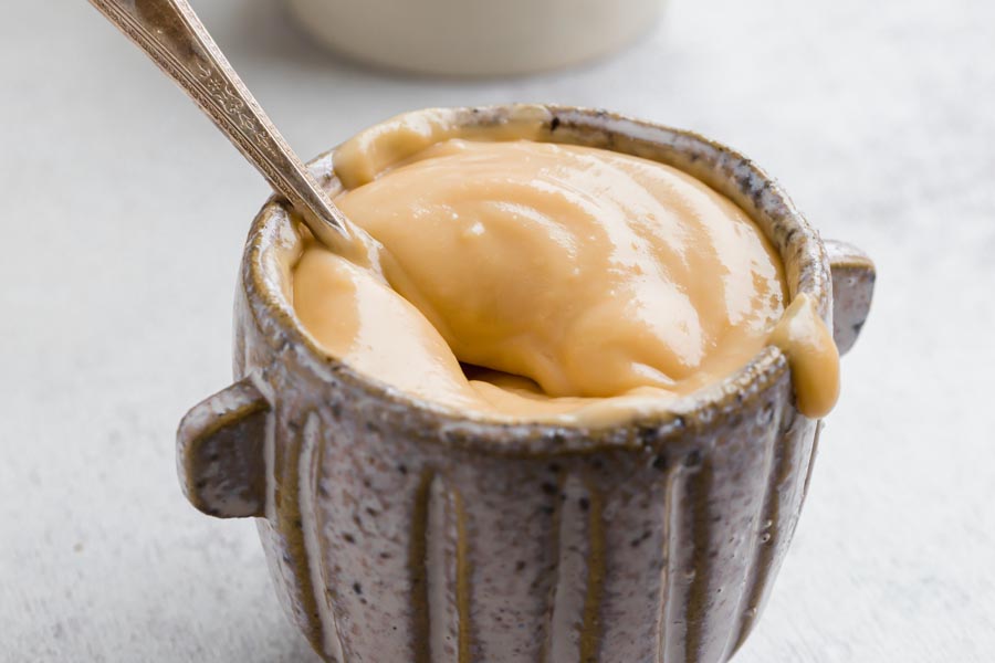 A spoon inside the thick, creamy, caramel colored sweetened condensed milk.
