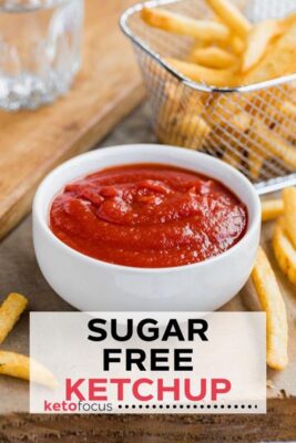 ketchup in a small white bowl with a wire basket containing french fries behind it