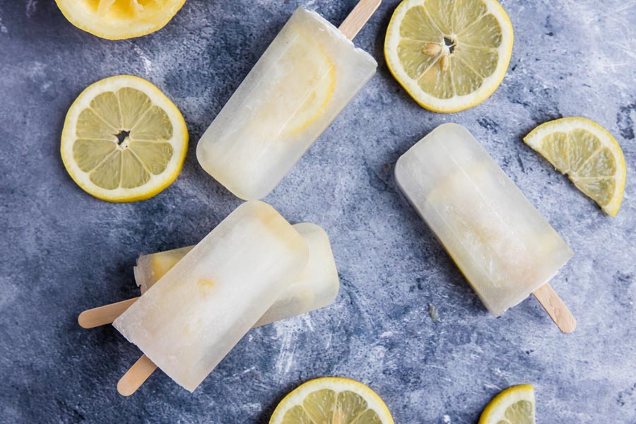 sugar free lemon popsicles scattered and stacked on a blue background