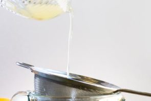 pouring lemon juice through a strainer