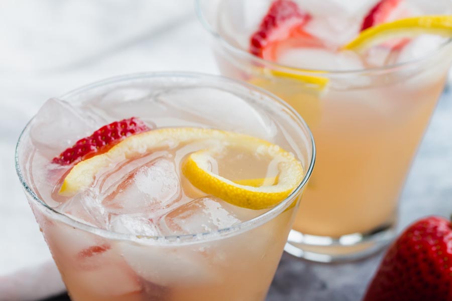 close up of two glasses with ice and pink lemonade in them