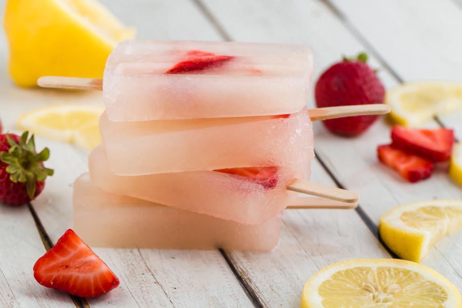 pink popsicles stacked up with sliced strawberries and lemons