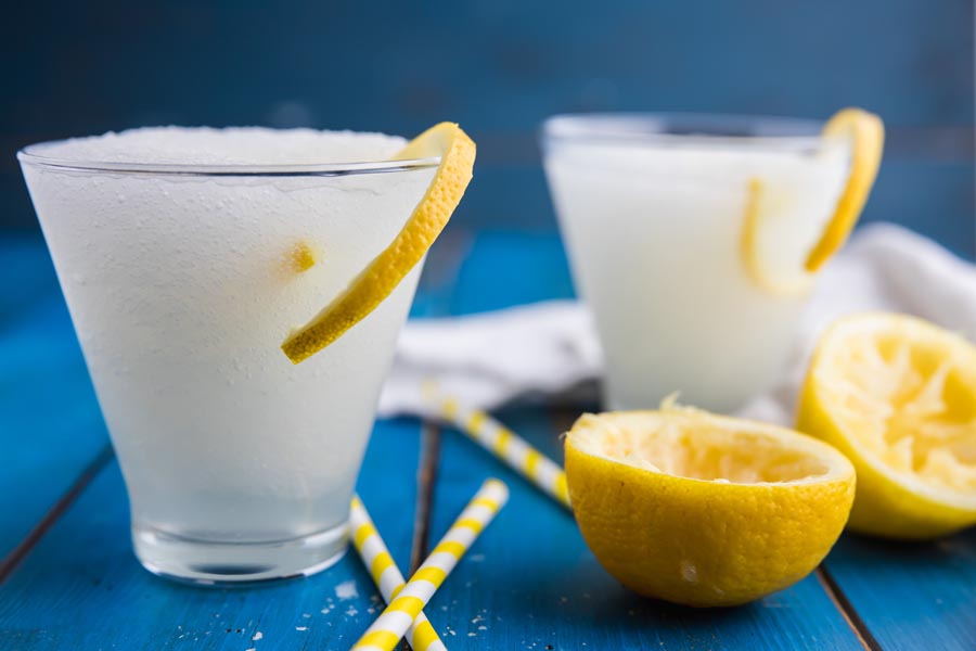 slushy vodka lemonades in two cocktail glasses with lemon curls hanging out