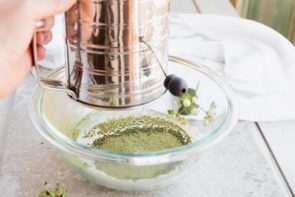 sifting green tea powder into a bowl using a sifter